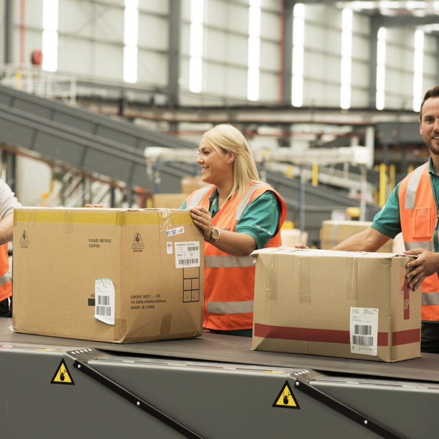toll workers holding boxes on conveyor belt