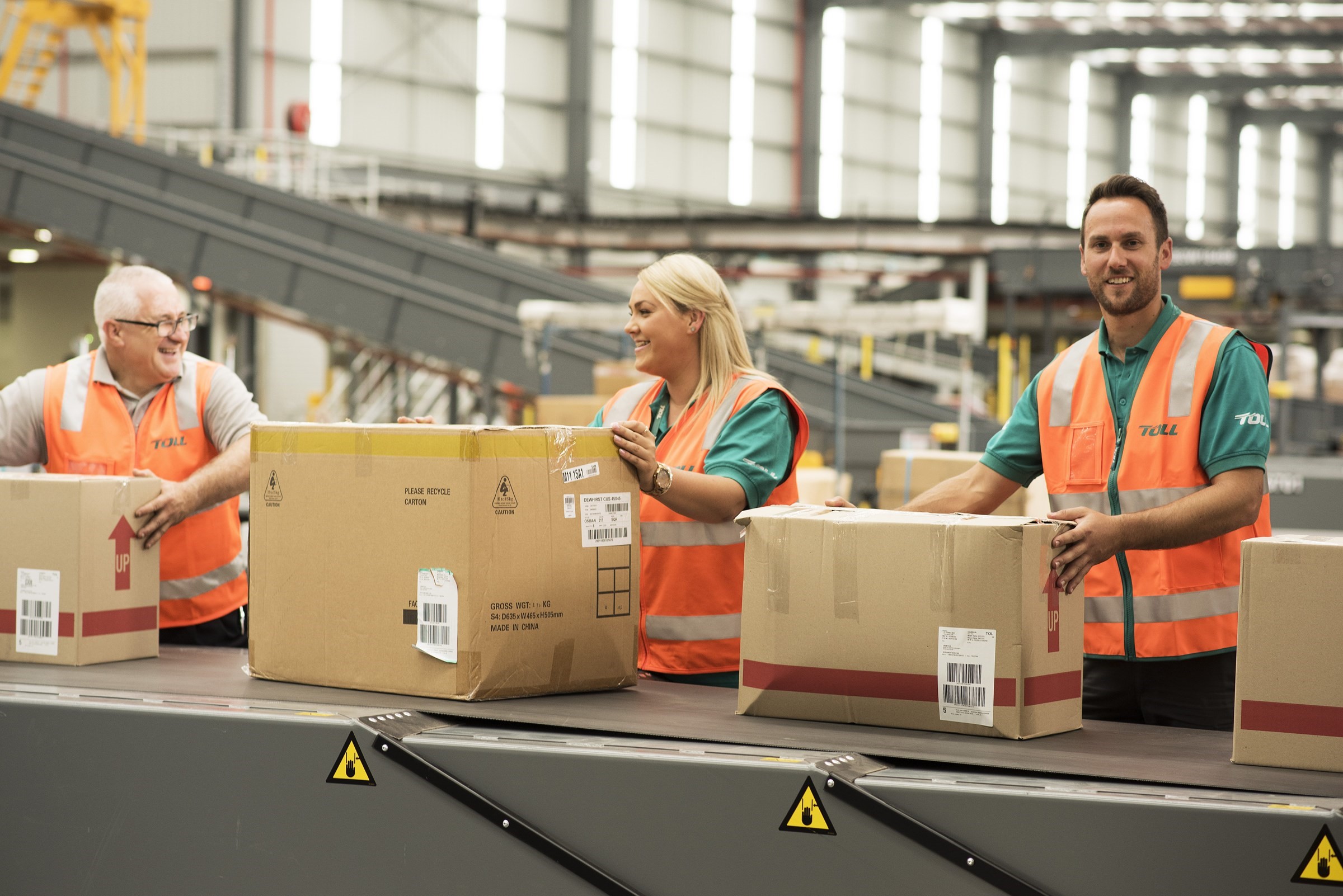 toll workers holding boxes on conveyor belt