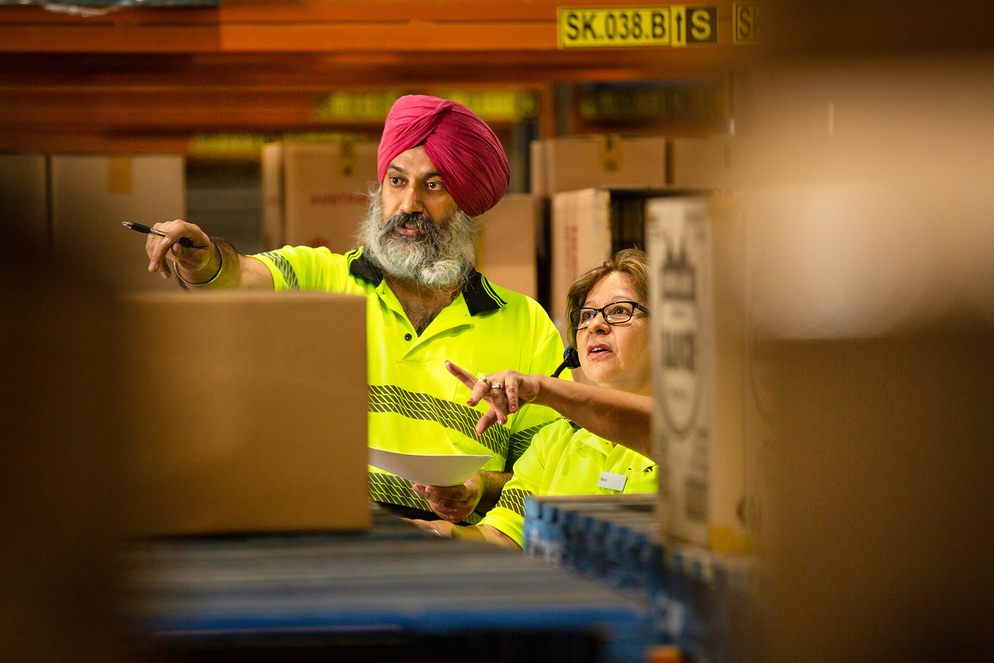 two warehouse workers pointing in same direction